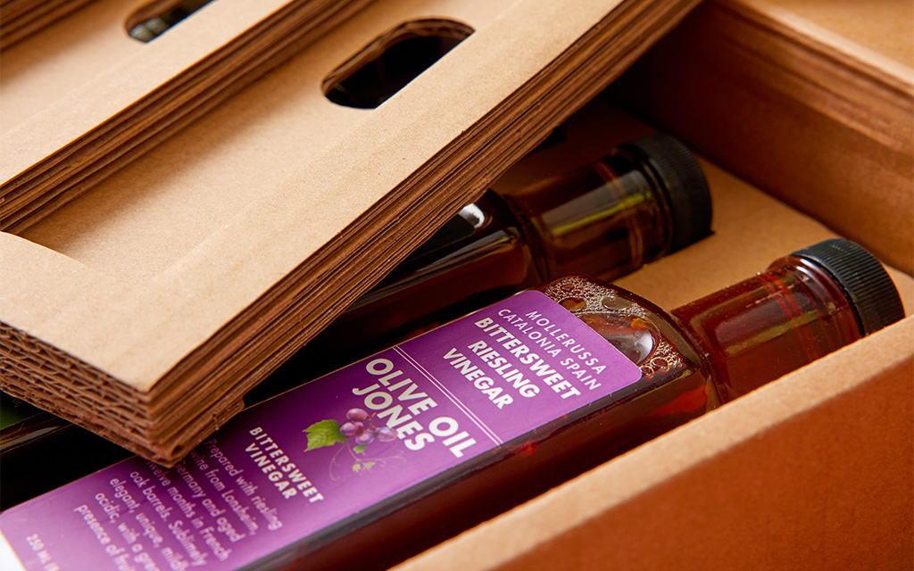 Corrugated packaging insert cradling OLIVE OIL JONES glass bottles using structural packaging engineering.