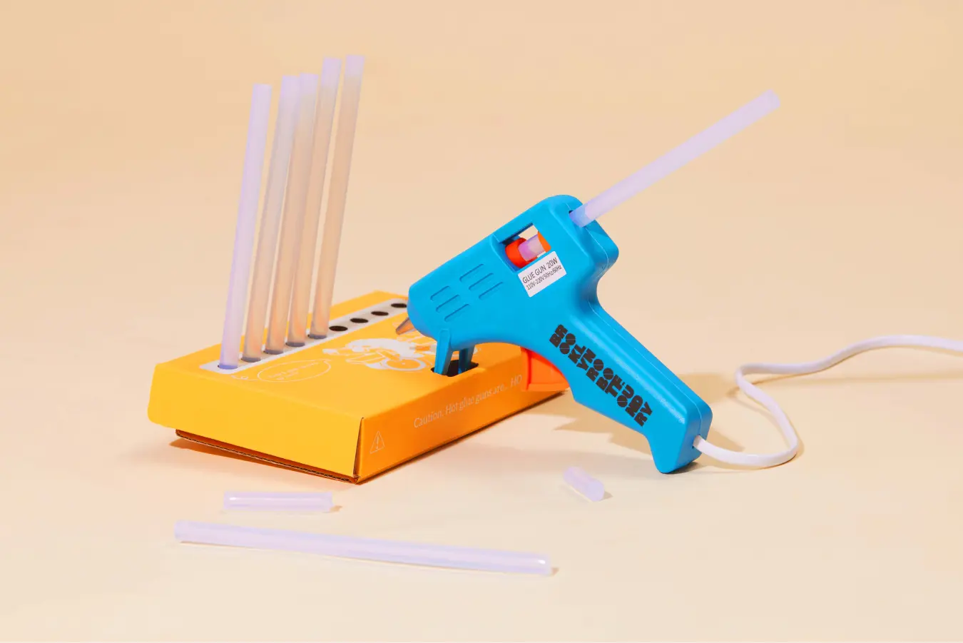 Blue hot glue gun on vibrant educational toy packaging with glue sticks for creative projects.