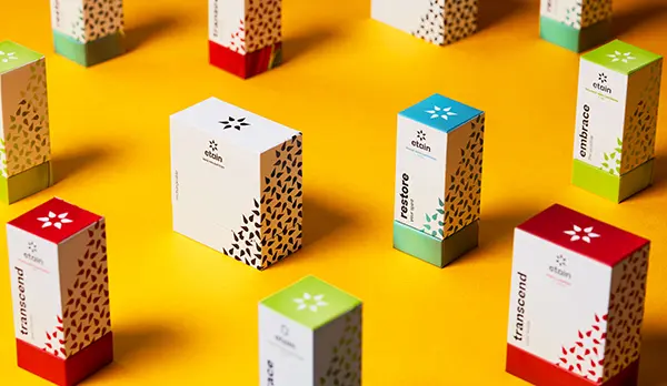 Etain custom packaging boxes with premium satin-touch finish arranged on a vibrant yellow background by Zenpack.