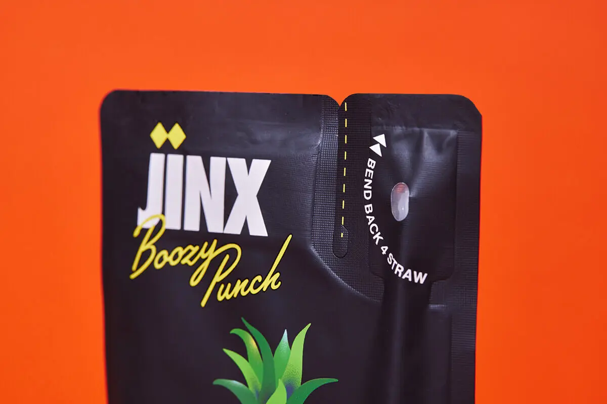 Close-up of Jinx Drinx flexible pouch showing tear notch and straw hole feature.