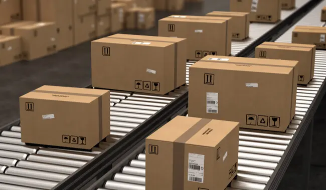 Corrugated cardboard boxes moving on warehouse conveyor belts for Zenpack packaging logistics services.