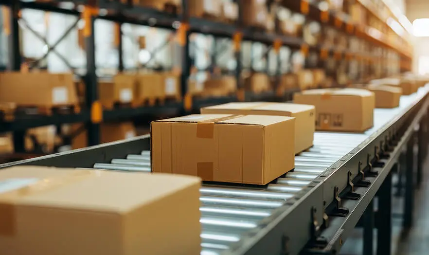 Cardboard boxes moving on a roller conveyor belt in a large fulfillment warehouse