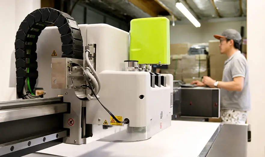 Technician operating a digital packaging sample cutting table