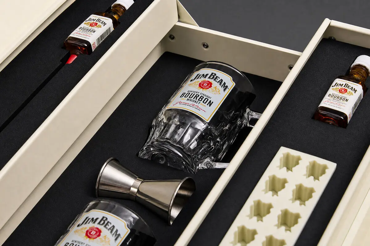Custom foam insert securing Jim Beam bourbon bottles and glassware in an influencer mailer by Zenpack.
