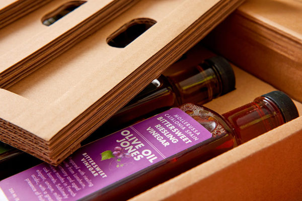 Custom corrugated cardboard inserts protecting Olive Oil Jones glass bottles inside a shipping box.
